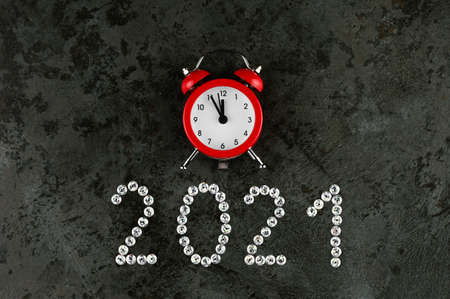 Happy New Year 2021 with alarm clock on concrete background.