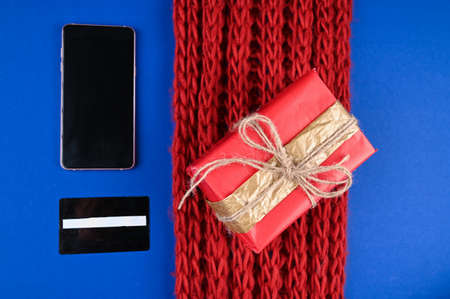Christmas online shopping background. Red scarf, credit card, smartphone and christmas present.の写真素材