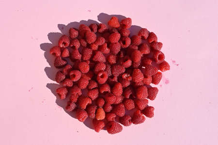 Raspberry circle with shadow on pink table.