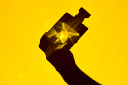 Shadow of perfume bottle in hand on a yellow background.の写真素材