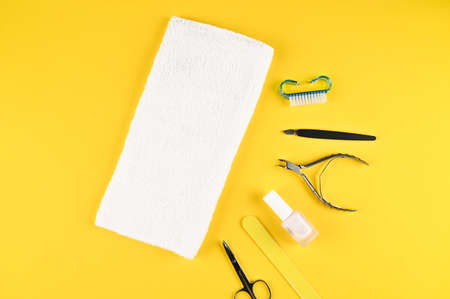 Female hands with perfect manicure are on the towel, on next to lay down devices for nail care. Yellow background, top view.の写真素材