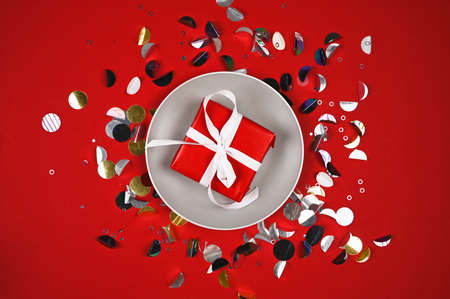 Top view of gift box on plate. Festive background with shiny sequins.