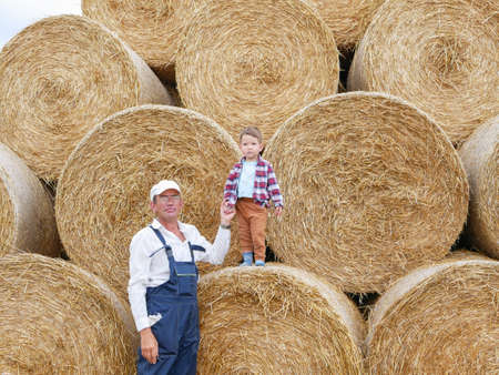 Little cute boy with grandfather on the background of straw rolls.の写真素材