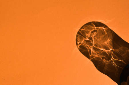Colorful glass cup shadow and flares on a orange background.