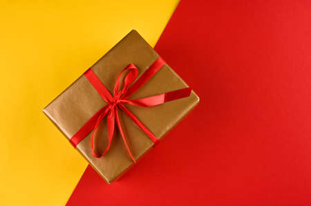 Christmas gift box against yellow-red background. Holiday greeting card.の写真素材