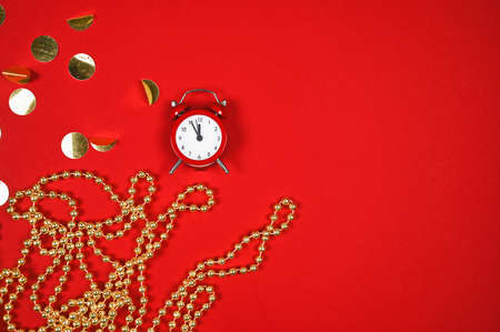 Christmas or New Year composition on red background with retro alarm clock and gold beads. Festive...