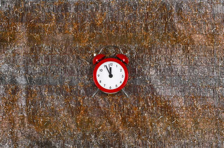 Red alarm clock on silver-gold shiny surface shows midnight. Party time concept. Copy spaceの写真素材