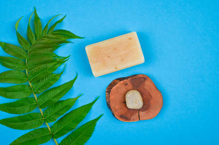 Flat lay with natural soap, wooden stand, stone and green branch.の写真素材