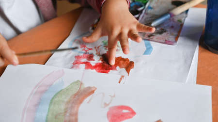 Little boy draws a rainbow on a sheet of paper in different colors. Home, game concept.