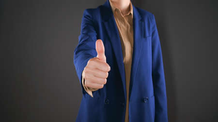 Cropped view of business woman shows thumb up. Expresses satisfaction or agreement. Isolated on gray background with copy space.の写真素材