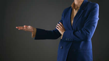 Woman in jacket pointing finger at copy space above her head. Young woman indicating something on blank studio wall with handの写真素材