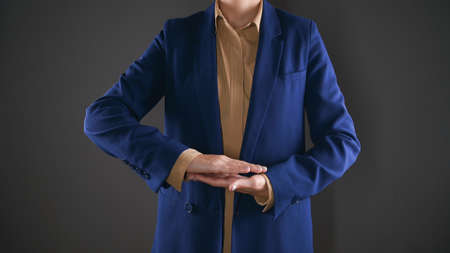 Business woman in suit showing her palms folded together. Concept advertisement product, isolated on gray backgroundの写真素材