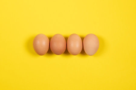 Four brown chicken eggs on a yellow background. Easter holiday conceptの写真素材