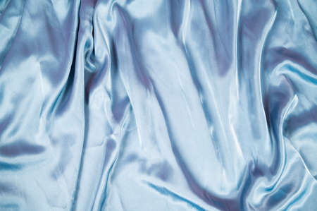 Light blue satin fabric background. Flowing wavy silk fabric background top viewの写真素材
