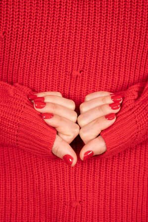 Beautiful female hands with red nails on knitted background. Empty place for text or logo. High quality photoの写真素材