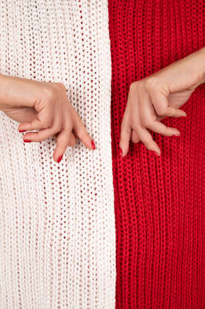 Tender female hands close up view on white and red knitted background. Winter manicure concept.の写真素材