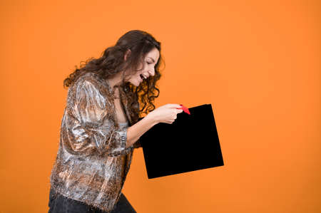 Portrait of a jouful woman holding empty black shopping bag. Concept of shopping purchases and...