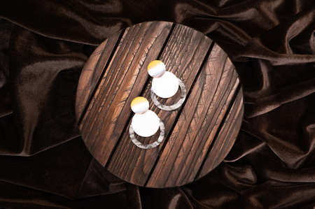 Stylish female earrings on dark wooden stand on wavy satin background. Top view of silver earrings with shell rock. High quality photoの写真素材