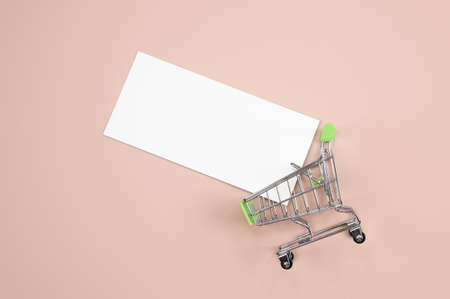 Creative shopping background with mini shopping cart and empty card in it on pink background with copy space. Black friday and sales concept .. High quality photoの写真素材