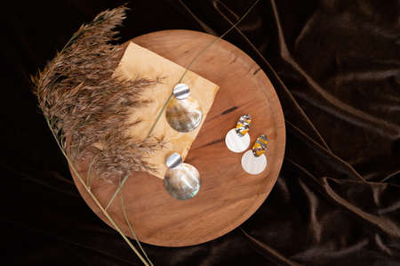 Graceful background with stylish earrings, pampas grass and folded silk textile. Cozy stilllife backdrop. Fashion and women blog concept. High quality photoの写真素材