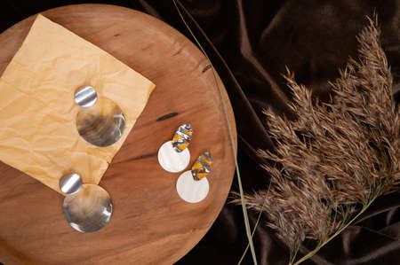 Stylish earrings on wooden stand, pampas grass and folded silk textile. Cozy stilllife backdrop. Fashion and women blog concept. High quality photoの写真素材