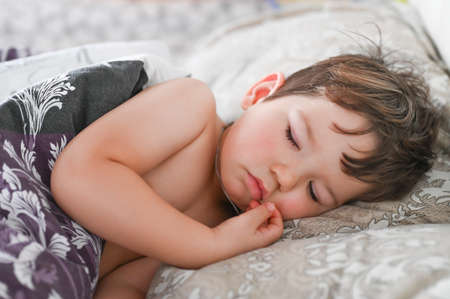 Adorable little boy sleeping in bed. High quality photo