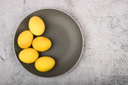 Pastel yellow easter eggs on a gray plate, concrete background with copy space. High quality photoの写真素材