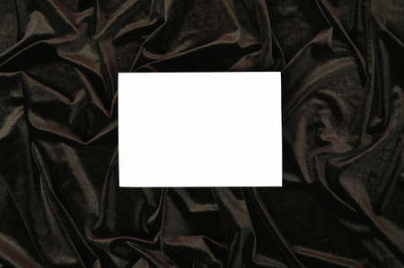 White invitation card mockup on a dark wavy velvet fabric. Flat lay. High quality photo