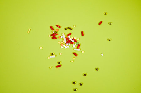 Different medicine pills, tablets on green background. Many pills and tablets with space for text,...