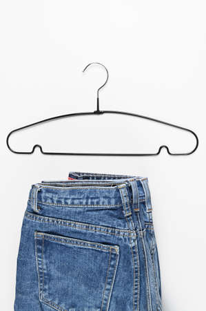 Denim Jeans and black hanger isolated on white. Textile industry and business concept. Shopping and...