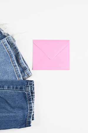 Cropped view of blue jeans and pink envelope with copyspace for sale text or business isolated on white, top view. Gift certificate concept. High quality photoの写真素材