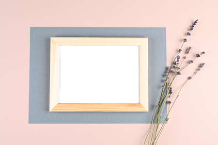 Horizontal wooden photo frame with white blank card and flowers on pastel pink background. Mock up...