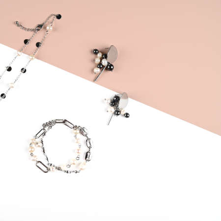 Set of chain choker with pearls, earrings and bracelet on pink white background. Trendy stylish jewelry. Female blog. High quality photoの写真素材