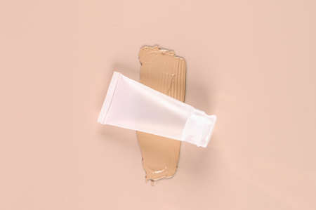 Concealer mat tube and cream smear on pink background. Beige foundation swatch. High quality photoの写真素材