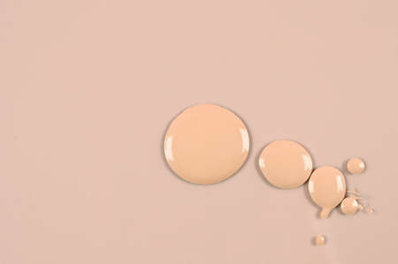 Beige nude liquid foundation set, concealer smear smudge drop. Cosmetic liquid foundation, concealer or moisturizer on pink background with copy space. High quality photoの写真素材