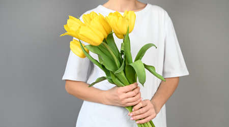 Woman holds tulips in her hands. Florist girl gathered a bouquet. Beautiful yellow flowers. High quality photoの写真素材