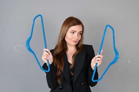A sad young woman looks at the empty hangers. Nothing to wear. High quality photoの写真素材