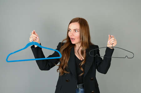 An astonished surprised woman holds empty hangers. Sale, Need of shopping concept. High quality photoの写真素材