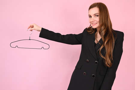 Young happy woman holding black empty hanger over pink background. Shopping concept. High quality photoの写真素材