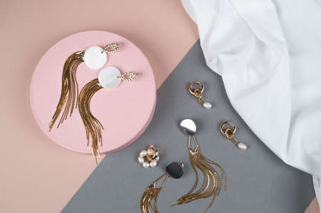 Stylish golden jewelry with pearls on pink gray background. Woman trendy fashion accessories arrangement. ... High quality photoの写真素材