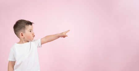 Funny boy pointing up to empty place on pink backgroun, banner for advertising product. High quality photoの写真素材