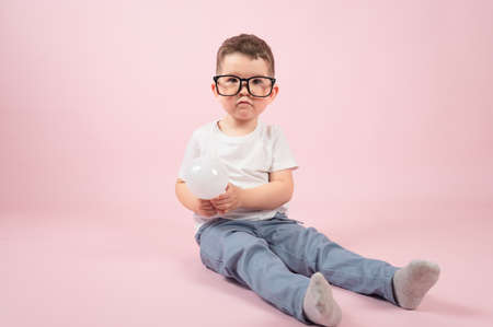 The cute little boy holds a light bulb in his hand on pink background. Education concept. High quality photoの写真素材