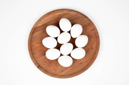 White eggs on a wooden plate on a white background. Organic eggs. ... High quality photo
