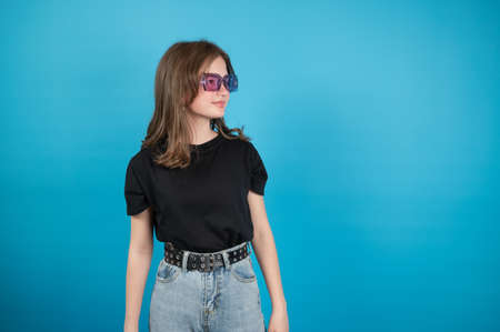 Teen girl in violet sunglasses on blue background. High quality photoの写真素材