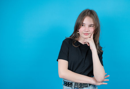 Close-up portrait of confused and pensive teenage girl isolated on blue. Awkward age concept. High quality photoの写真素材