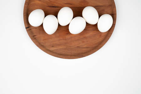 Top view of white eggs on a round wooden plate isolated on white. Organic eggs and healthy nutrition...