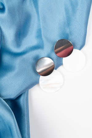 Top view of stylish earrings on wavy blue satin surface. Fashion and style concept. Top view. High quality photoの写真素材
