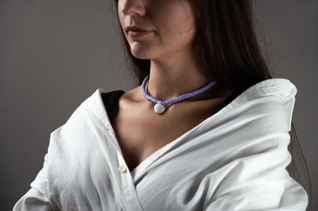 Jewelry shop. Young woman demonstrating stylish necklace with heart shaped pendant, cropped view....