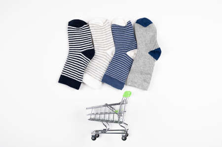 Little baby socks over shopping cart isolated on white. Consumer shopping concept. High quality photoの写真素材