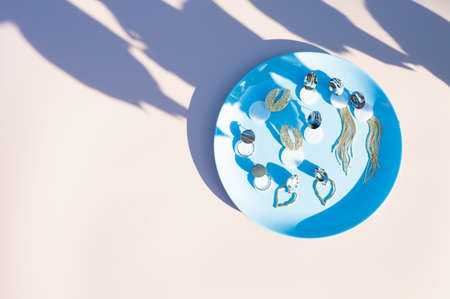 Top view of stylish earrings on blue plate. Pastel background with copy space. High quality photoの写真素材